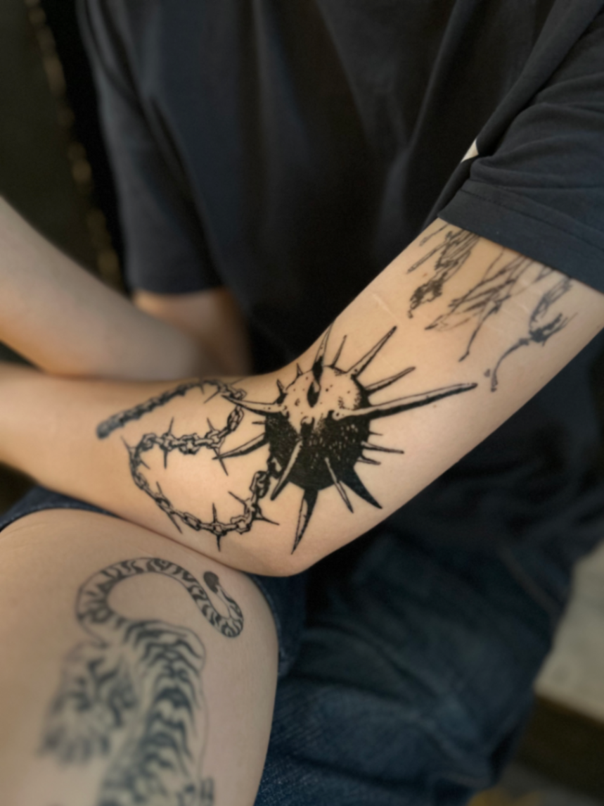 Blackwork thorn sun and chain tattoo on the arm