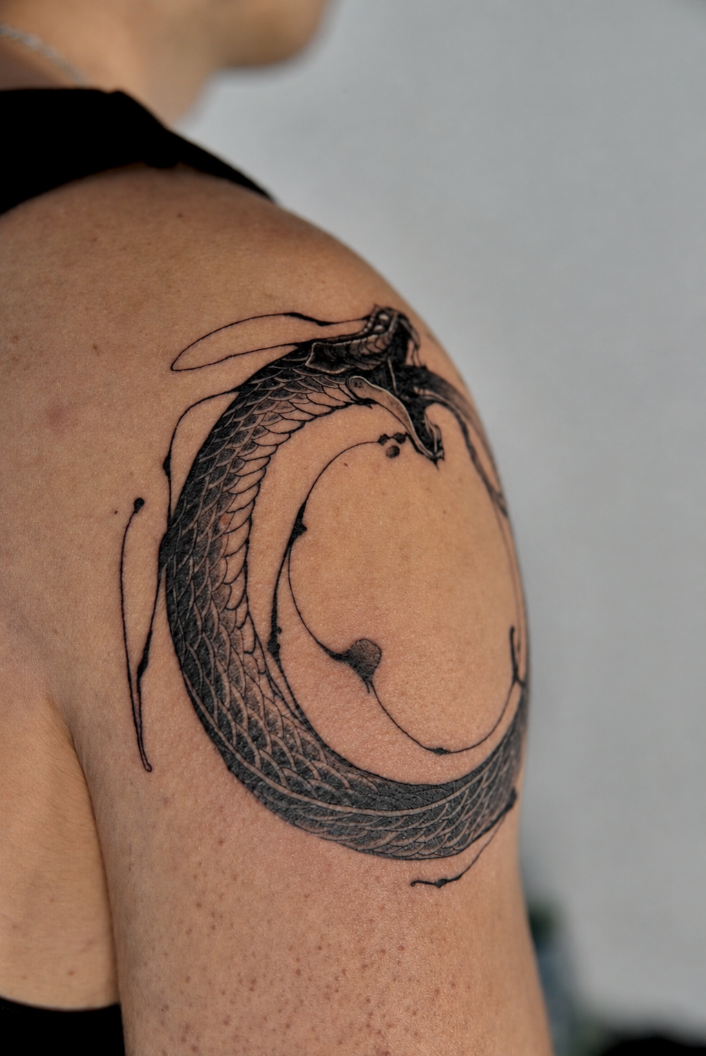 Black and grey ouroboros serpent tattoo on the shoulder