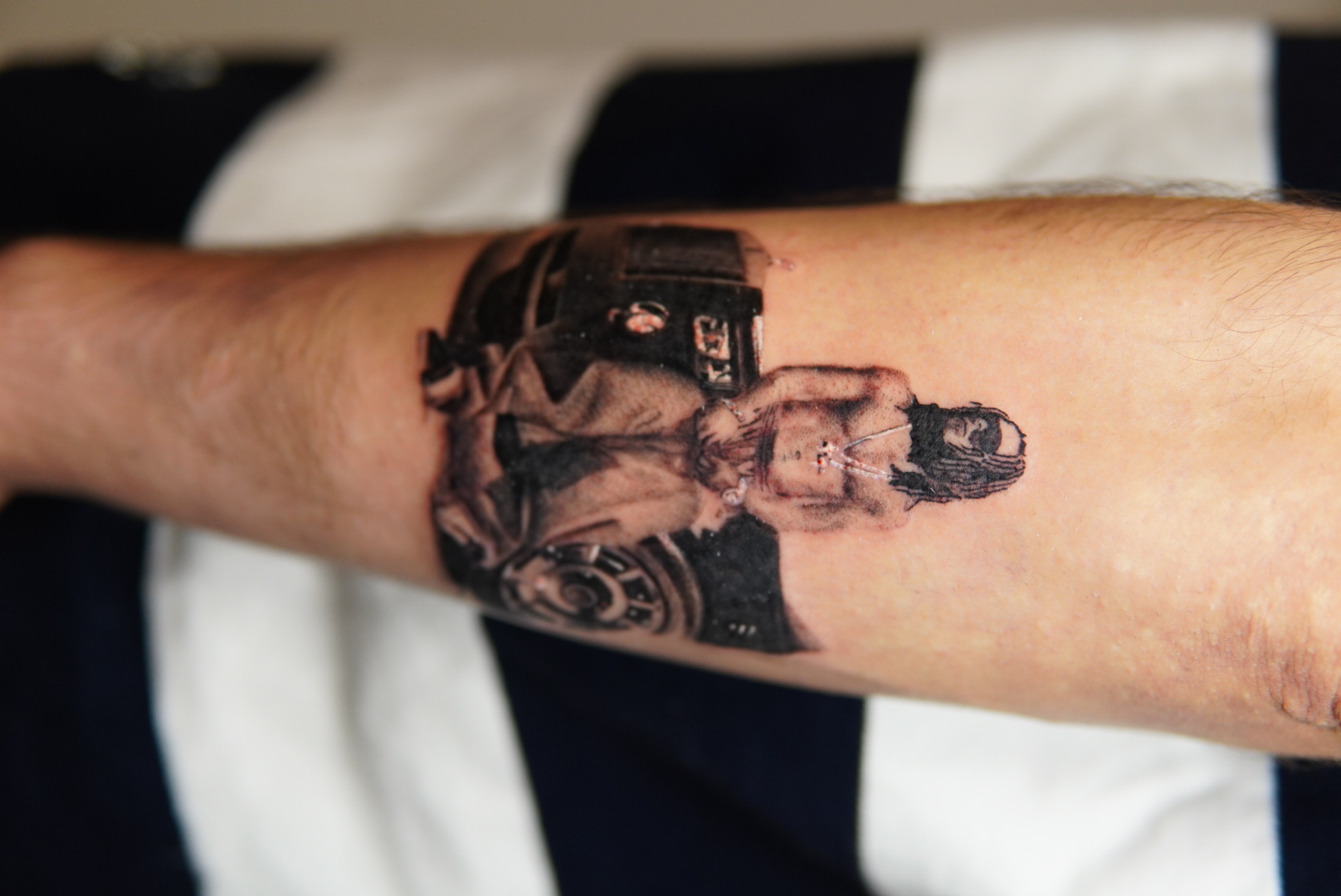 Black and grey realism tattoo of a figure seated in front of a classic car